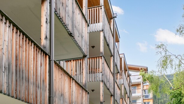 Un edificio de varios pisos con balcones y fachada de madera.