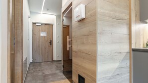 Un pasillo moderno con suelo de madera, una puerta de madera y una lámpara fijada a la pared.