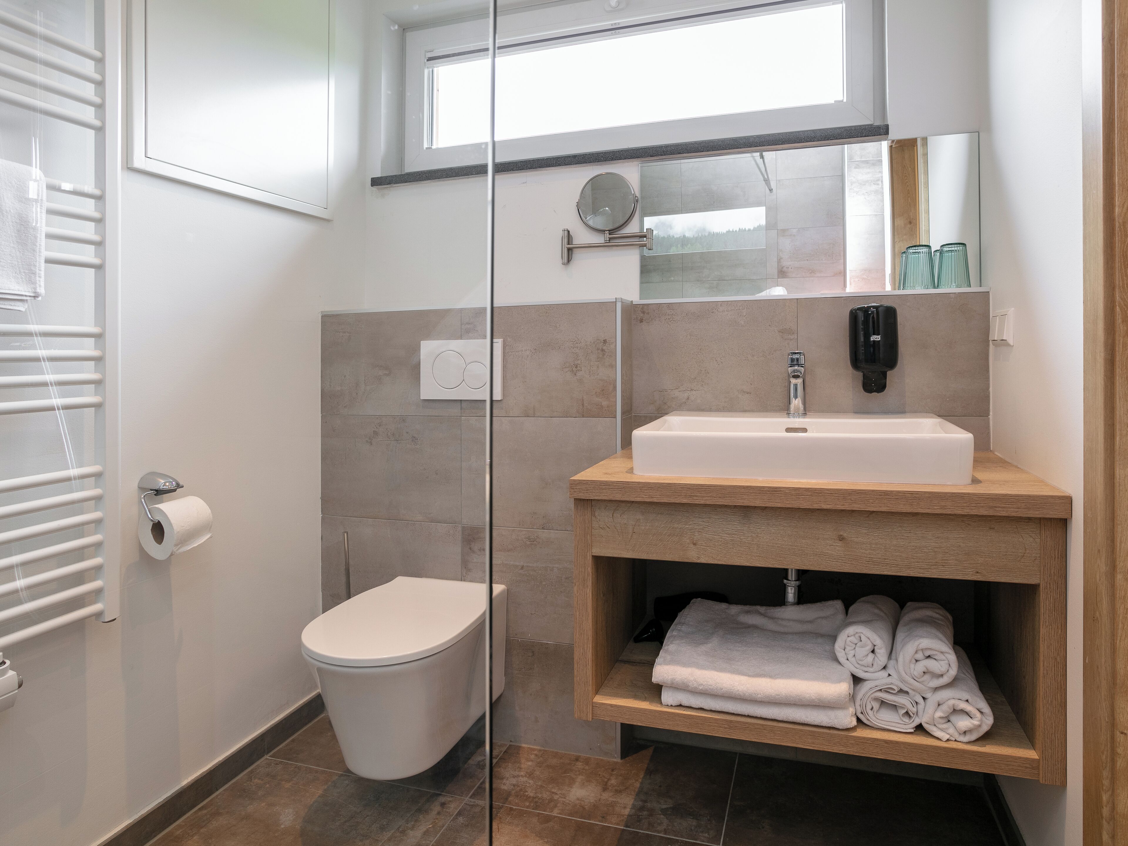Un baño moderno con inodoro, lavamanos y toallero.