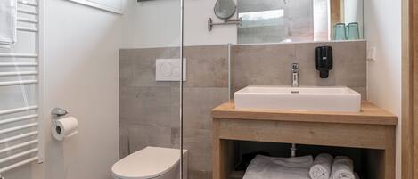 Un baño moderno con inodoro, lavamanos y toallero.