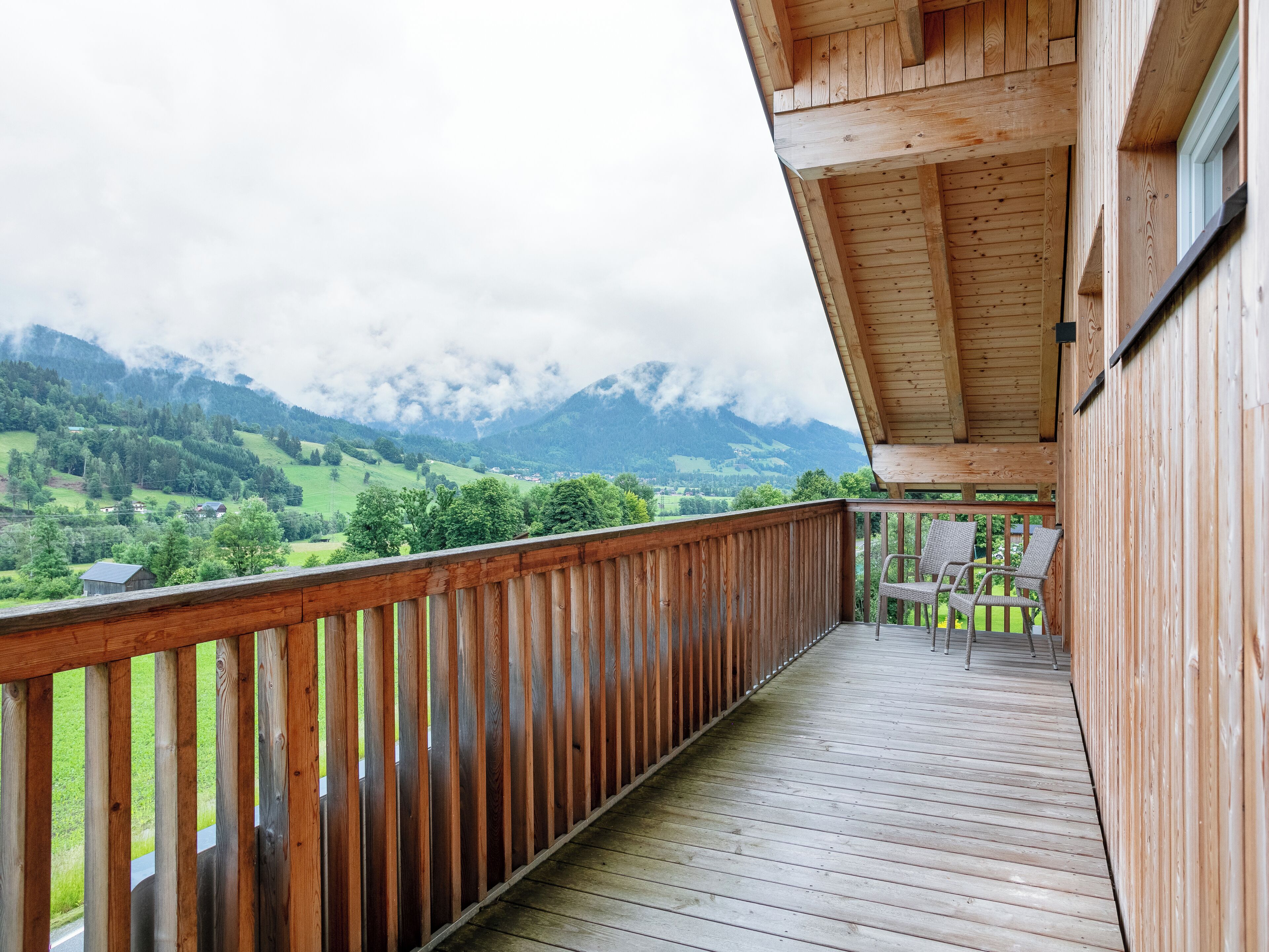 A wooden balcony with a view of a mountainous landscape.