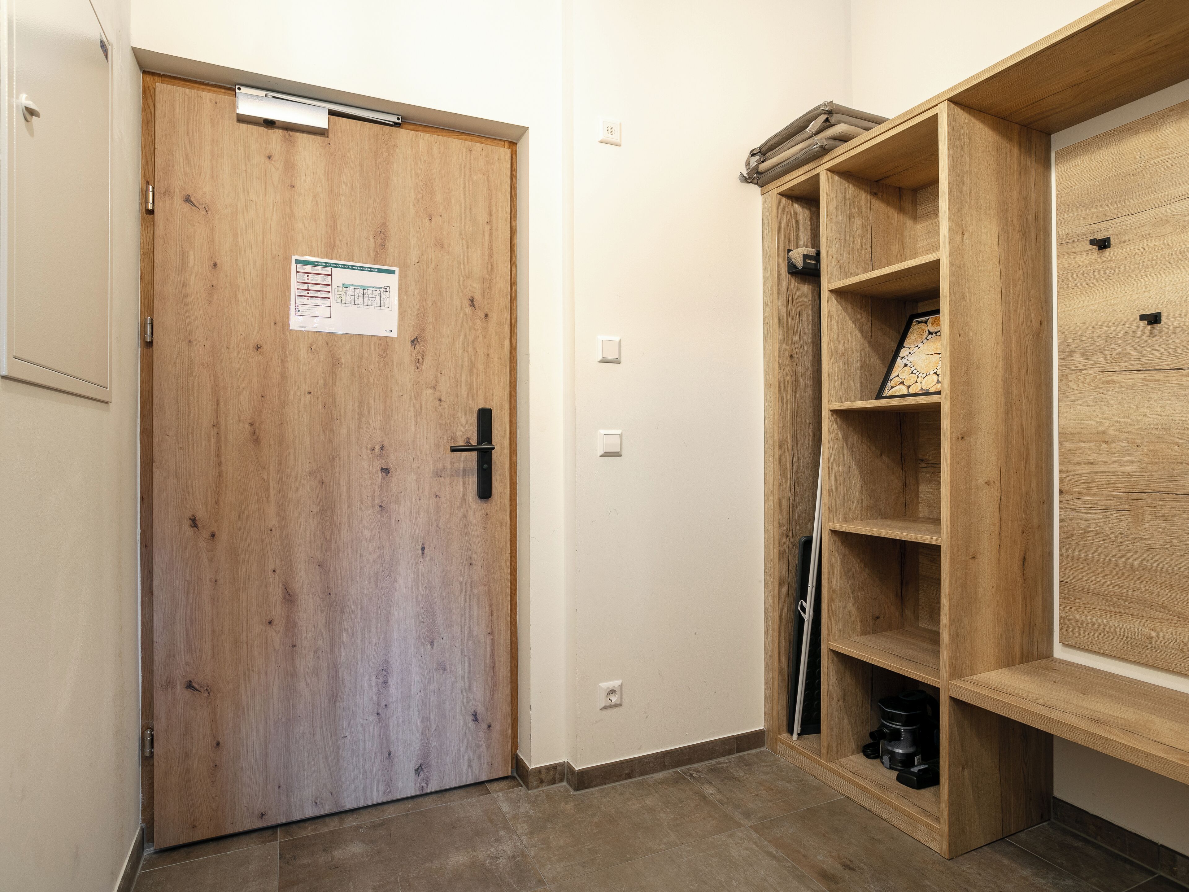 A wooden door with a sign, a shelf unit with a picture frame, and a black object on the floor.