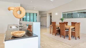 Et moderne køkken med en stor ø, rustfrie stål-hvidevarer og en markant hængende lampe.