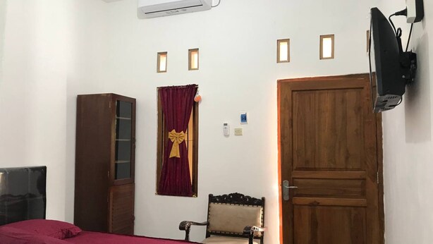 Ein Schlafzimmer mit einem Bett, einem Holzschrank, einem Stuhl, einer Holztür und einem an der Wand befestigten Fernseher.