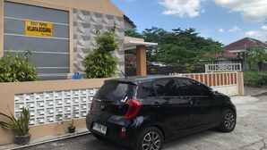 Ein schwarzes Auto vor einem Gebäude mit der Aufschrift "KOST PUTRI WIJAYA KUSUMA By Nurse".