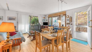 Un comedor acogedor y bien iluminado con mobiliario de madera, un televisor y vistas al exterior.
