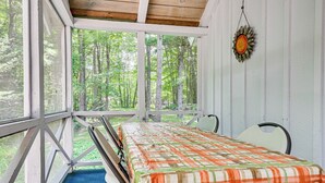 Una cabaña con una cama, un ventanal y vistas al bosque.