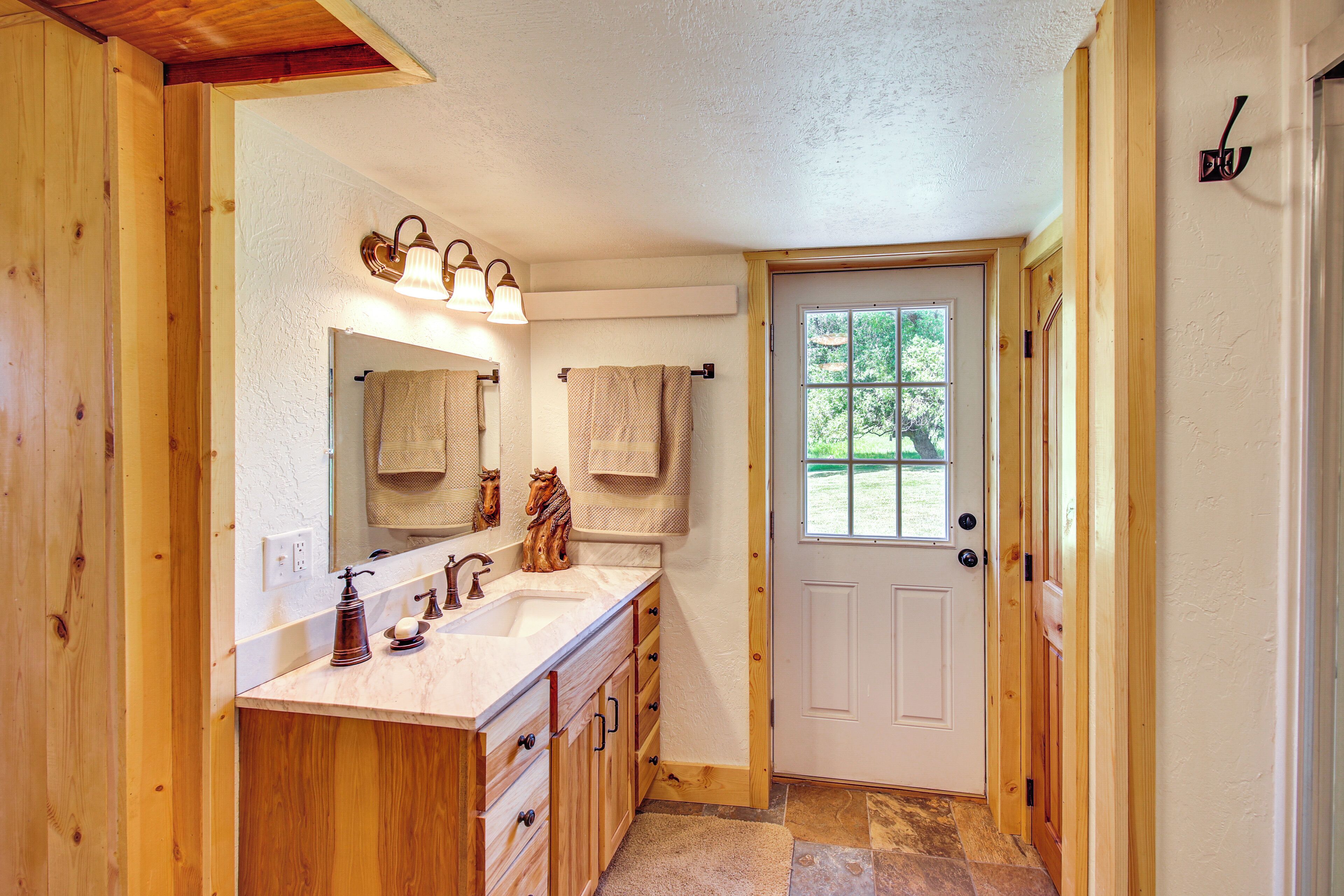 A bathroom with wooden cabinetry, a double sink, and a mirror with a towel rack.