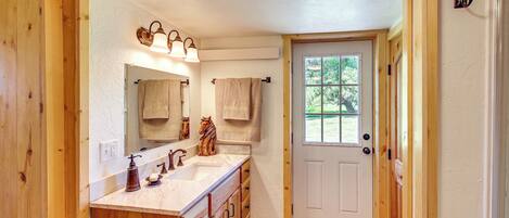 A bathroom with wooden cabinetry, a double sink, and a mirror with a towel rack.
