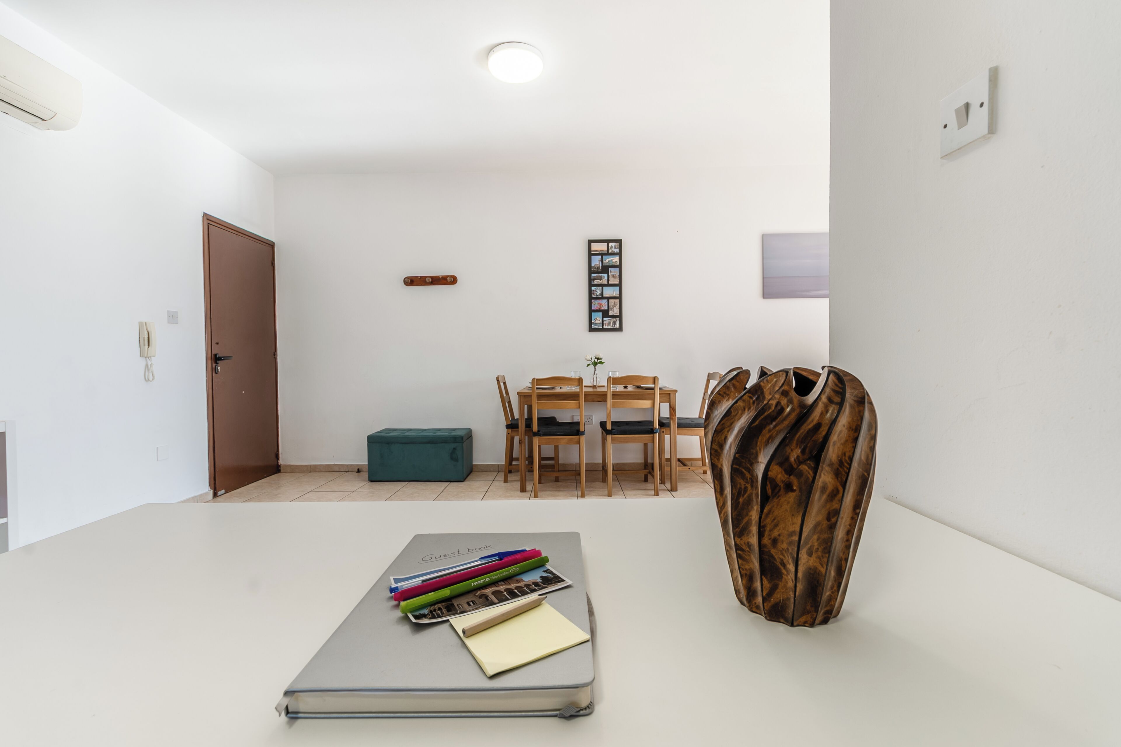 A modern room with a desk, a chair, a table, a vase, and a door.