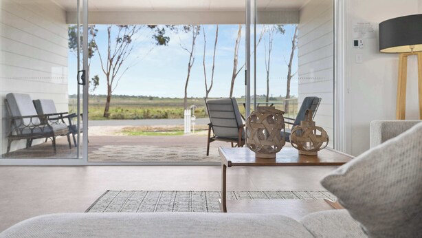 A modern living room with a glass door leading to an outdoor patio, furnished with a sofa, chairs, and decorative items.