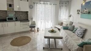 A modern living space with a kitchen, dining area, and a sofa set. - Flat El Retiro 4 people with swimming pool. (Dénia)