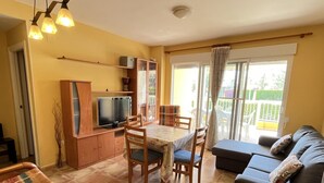 A cozy living room with a sofa, a dining table with chairs, a TV, and a balcony with a view. - 2-bedroom flat in Playasol II (Dénia)