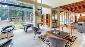 A spacious living area with a large window, a foosball table, a sofa, and a coffee table. - Scenic Haven Cozy Pet Friendly Retreat (Mexico City)