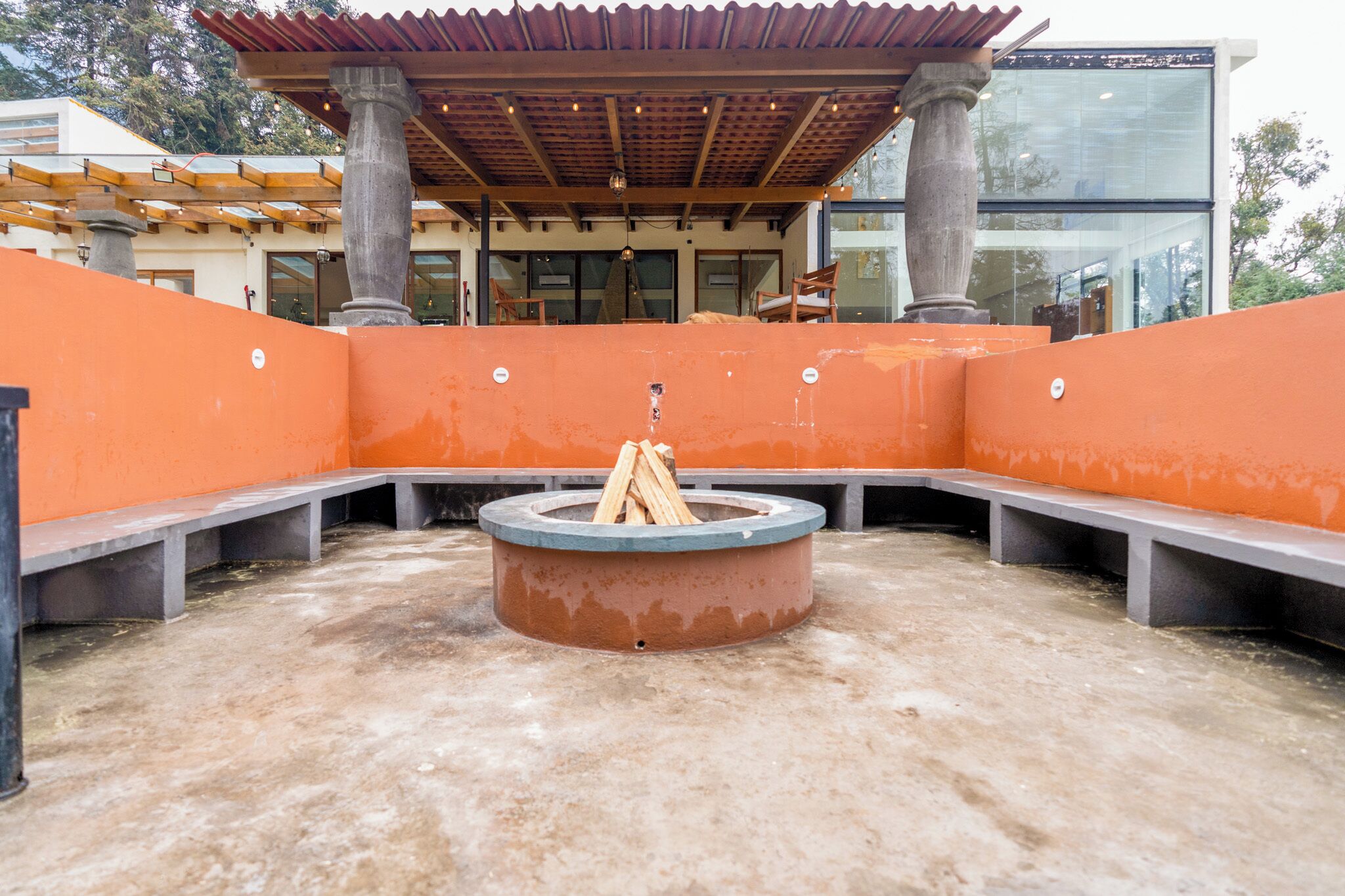 Un espace extérieur aménagé avec un foyer circulaire et des bancs.