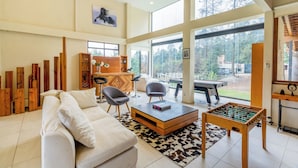 A spacious living room with a sofa, chairs, a foosball table, and a wooden cabinet. - Scenic Haven Cozy Pet Friendly Retreat (Mexico City)