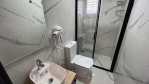 A modern bathroom with a marble floor, a sink, a toilet, and a glass shower enclosure. - Alp Ateş Suit  (Ayvacik)