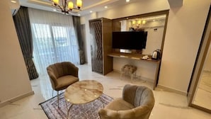 A modern living room with a sofa, armchair, coffee table, and a TV mounted on a wall. - Alp Ateş Suit  (Ayvacik)