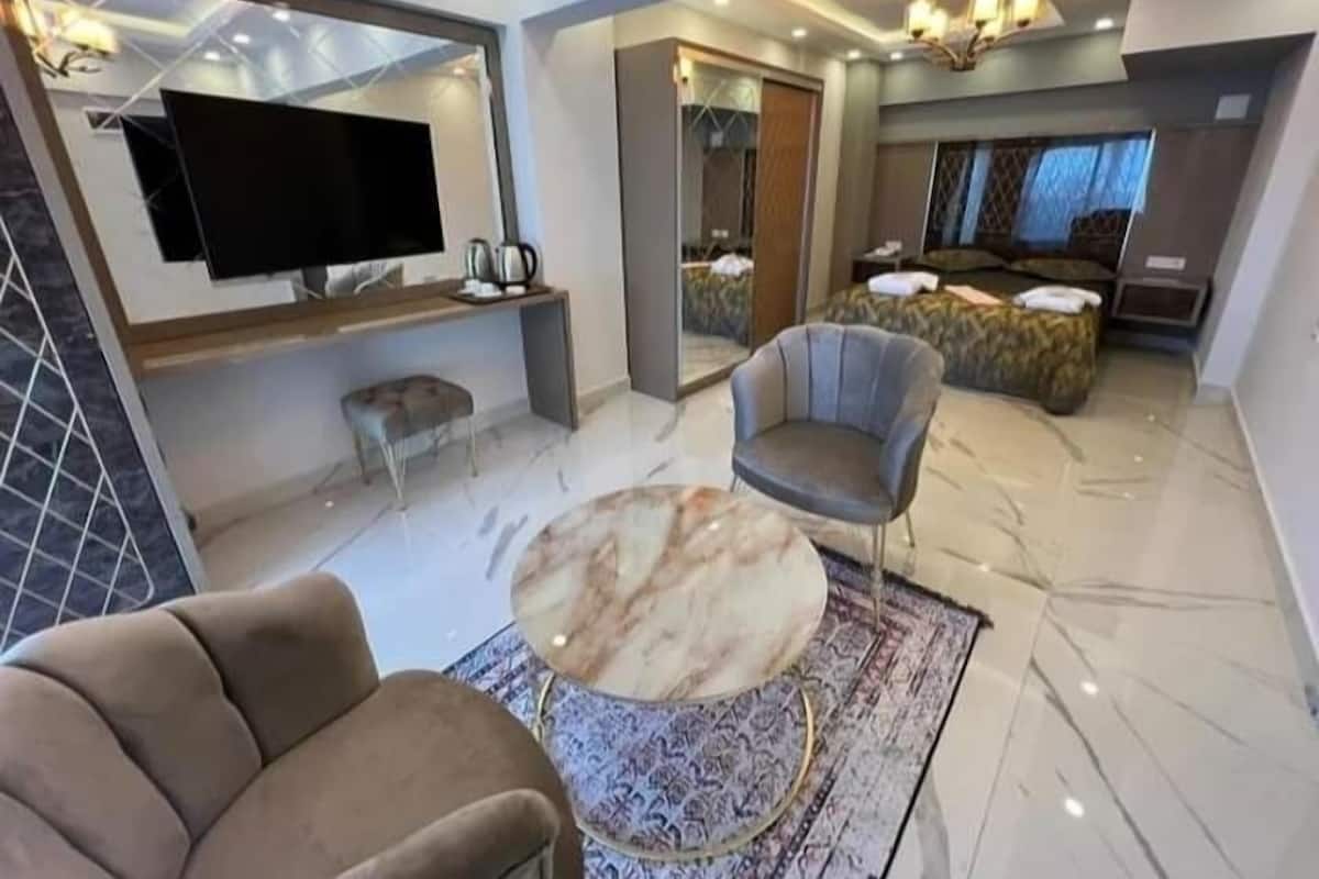 A modern living room with a flat-screen TV, a round coffee table, and a comfortable sofa.