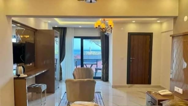 A modern hotel room with a large bed, a desk, a chair, and a TV. - Alp Ateş Suit  (Ayvacik)