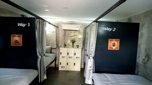Een kamer met twee bedden, een kledingkast en een klein kastje met vakken.