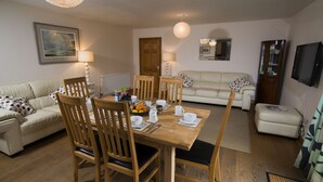 A dining area with a wooden table, chairs, and a sofa. - Drws Nesa - sleeps 6 guests  in 3 bedrooms (Pwllheli)