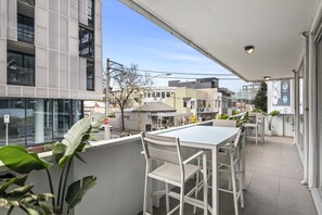 En balkon med hvide møbler, et vejskilt og en bygning med en facade af net.
