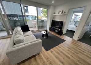 Ein modernes Wohnzimmer mit einer Couch, einem Couchtisch, einem Fernseher und einem Kamin.