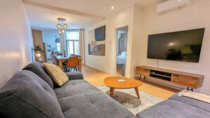 Ein modernes Wohnzimmer mit Ecksofa, rundem Couchtisch, Flachbildfernseher und einer Holz-Unterhaltungsecke.