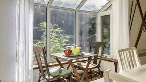 A room with a large window, a table with chairs, and a plant on the windowsill. - 5BR Chalet with Hot Tub & Lake Access (Mont-Blanc)
