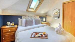 A bedroom with a skylight, a bed with a tray of breakfast, a nightstand, and a wooden wardrobe. - 5BR Chalet with Hot Tub & Lake Access (Mont-Blanc)