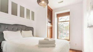 Ein Schlafzimmer mit einem Bett, einem Fenster und einer Wandleuchte.