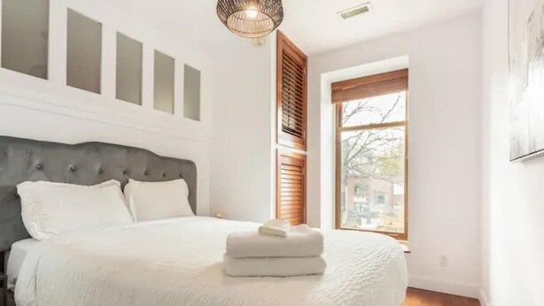 Une chambre à coucher avec un lit, une fenêtre et un luminaire fixé au mur.