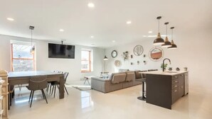 Une cuisine moderne avec un coin repas, un canapé et un téléviseur fixé au mur.