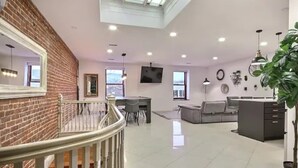 Un vaste espace de vie doté d’un haut plafond, d’un escalier, d’un coin repas et d’un espace détente avec un canapé et une table basse.
