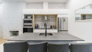Una cocina moderna con una isla central, armarios blancos y un horno empotrado.