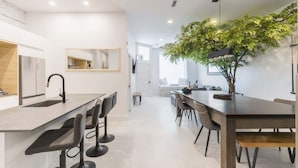 Una cocina moderna con comedor, un espejo grande y un árbol en el centro.