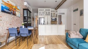 A modern kitchen with white cabinets, a dining area with blue chairs, and a blue sofa.