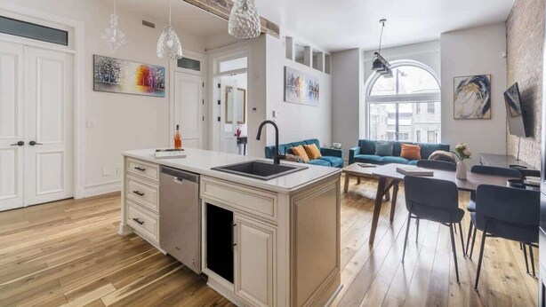 A modern kitchen with a central island, a dining area with chairs, a sofa, and artwork on the walls.