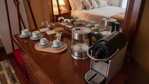 A hotel room with a wooden desk, tea set, coffee maker, and a microwave.