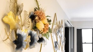 Eine Wand mit einer dekorativen Metall- und Glasgestaltung, die Blumen und Blätter zeigt.