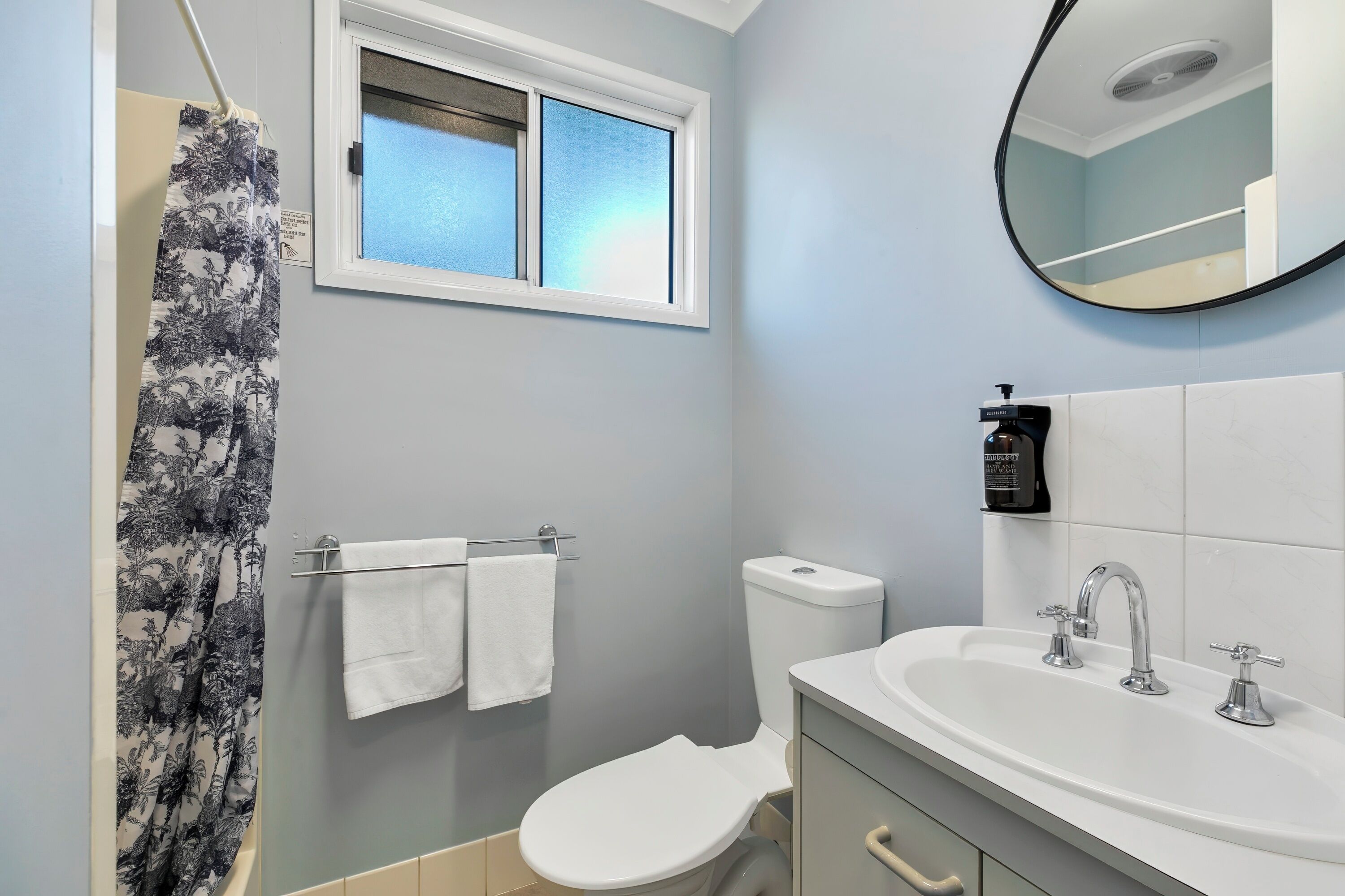 A bathroom with a toilet, sink, and shower curtain.