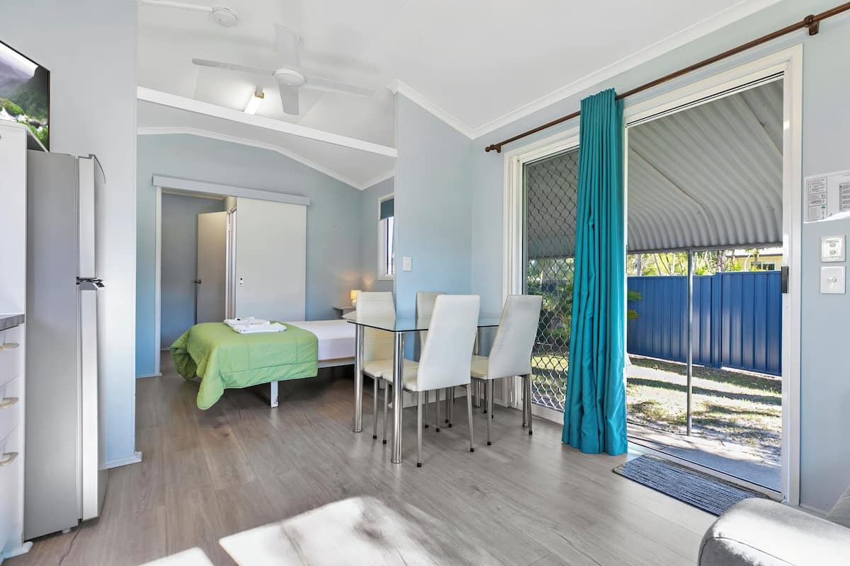 Une pièce de taille modeste comprenant un lit, une petite table et un coin repas avec des chaises.