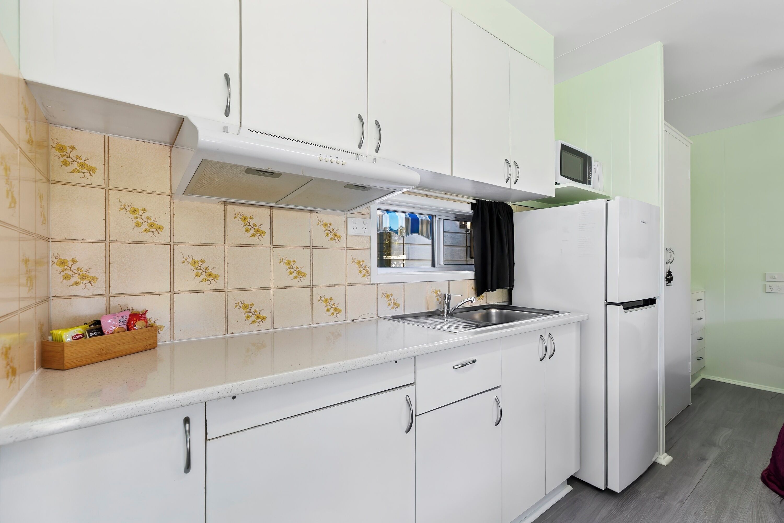 A kitchen with white cabinets, a microwave, and a refrigerator.