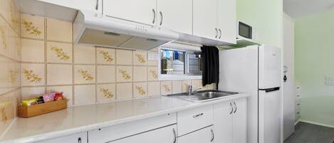 A kitchen with white cabinets, a microwave, and a refrigerator.