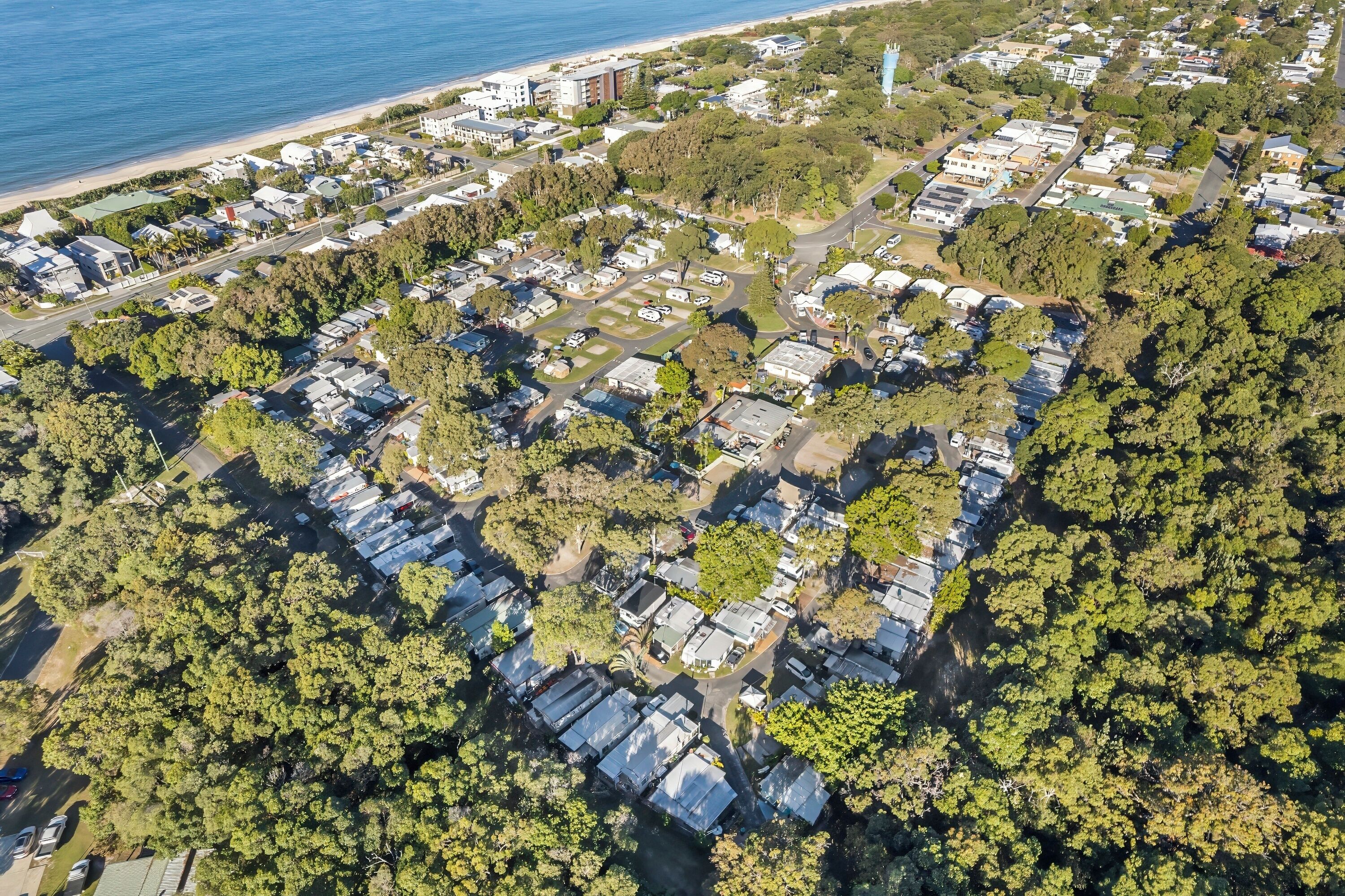 An aerial view of a residential area with houses, roads, and a beach.