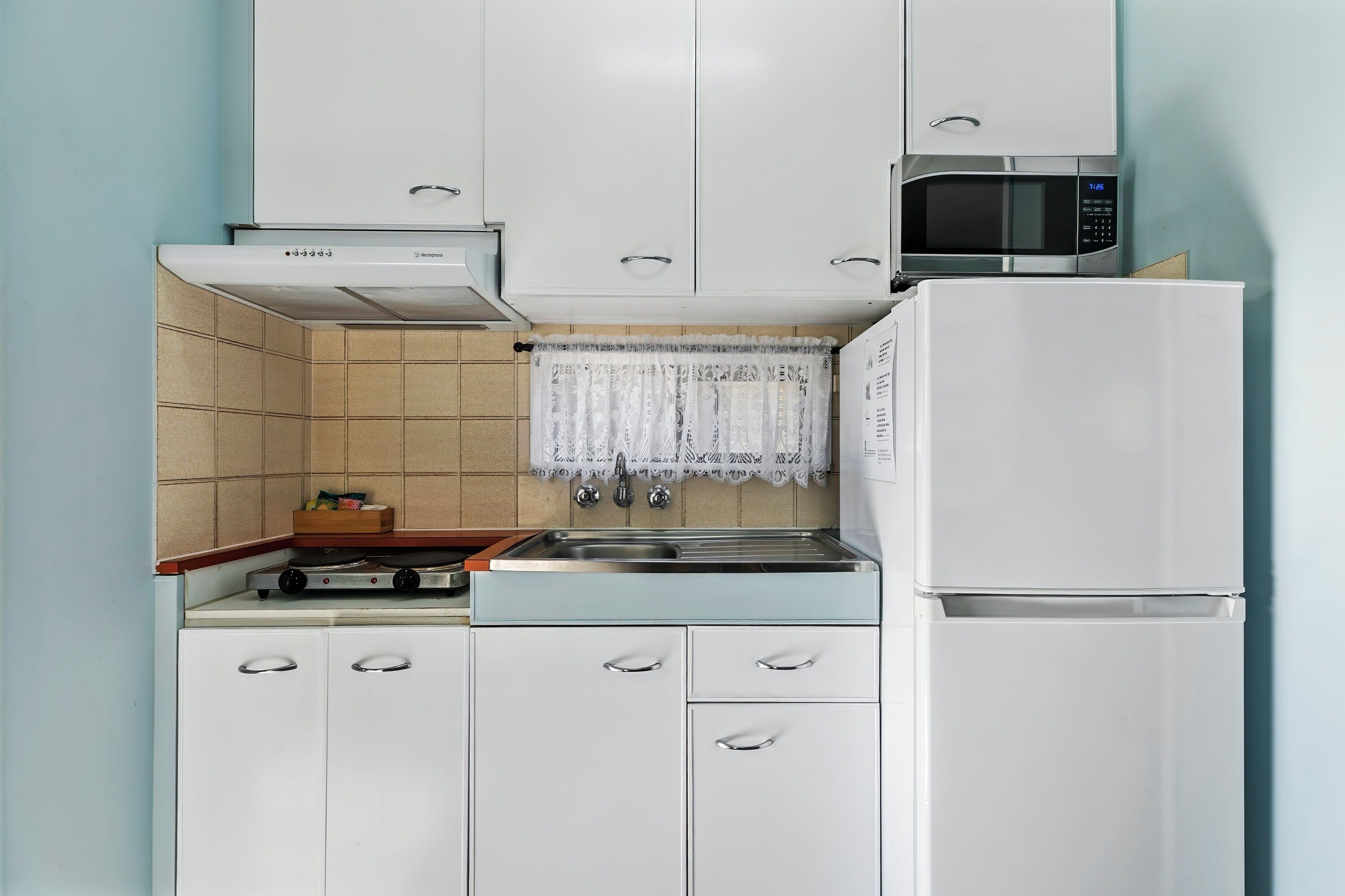 Une cuisine avec des meubles blancs, une cuisinière, un four à micro-ondes et un réfrigérateur.