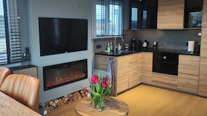 Une cuisine moderne équipée d’un téléviseur à écran plat, d’une cheminée, de meubles en bois et d’un coin repas avec des fauteuils en cuir.