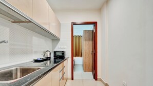 Une cuisine étroite avec un évier en acier inoxydable, un grille-pain et une porte en bois donnant sur une autre pièce.