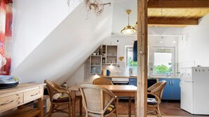 Un coin repas avec une table et des chaises en bois, une cuisine avec des placards bleus et un réfrigérateur blanc.